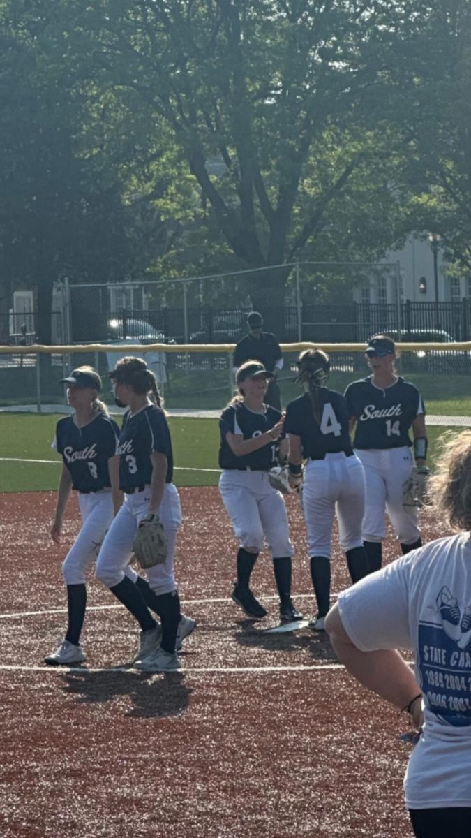 Charlie Harr ’26 playing second base and Maggie O’brien ’25 playing first base high fiving pitcher Mackenzie Waterson ’27 after a strikeout
